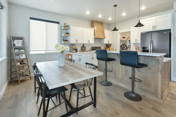 Kitchen featuring wood-finish flooring, white cabinetry, a kitchen island with seating, a built-in refrigerator, and recessed lighting