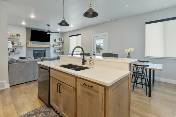 Kitchen island with light wood-finish cabinetry, light-toned countertops, and a double basin sink with a matte black faucet