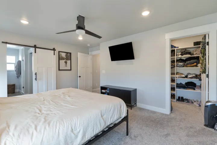 Recessed lighting, ceiling fan, carpet flooring, and a walk-in closet with built-in shelving