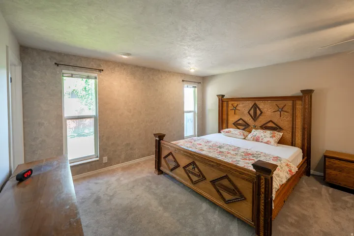 Textured accent wall, neutral carpeting, and recessed lighting
