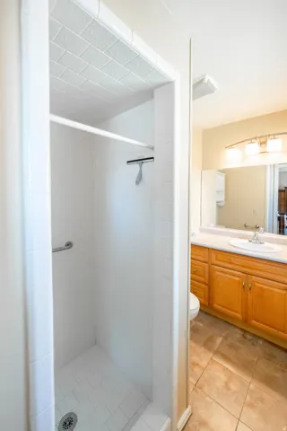 Walk-in shower with subway tile surround and white tile flooring