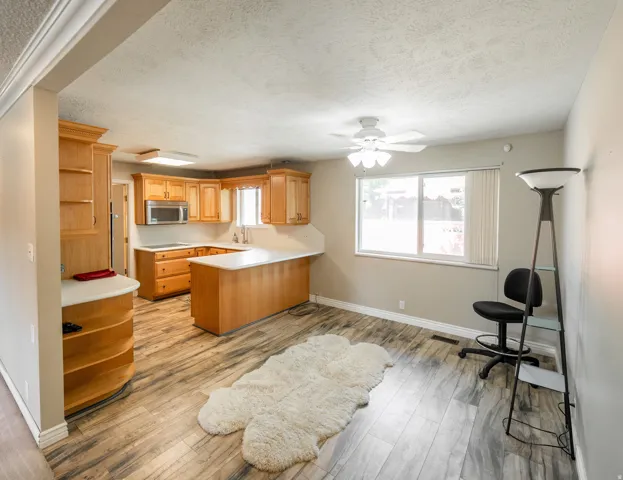 Kitchen featuring wood-finish flooring, wood cabinetry, white countertops, and stainless steel appliances