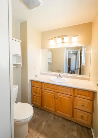Vanity with light wood-finish cabinetry, integrated sink, and expansive mirror