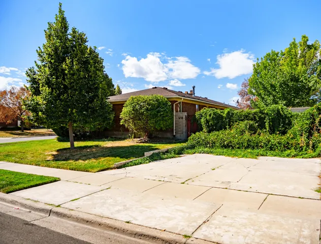 Expansive concrete parking pad, mature trees, and a brick-clad exterior