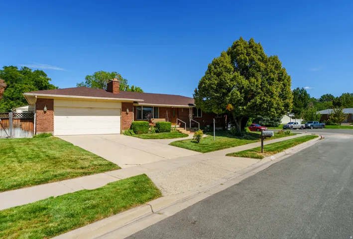Brick exterior with an attached two-car garage, concrete driveway, and mature front yard landscaping