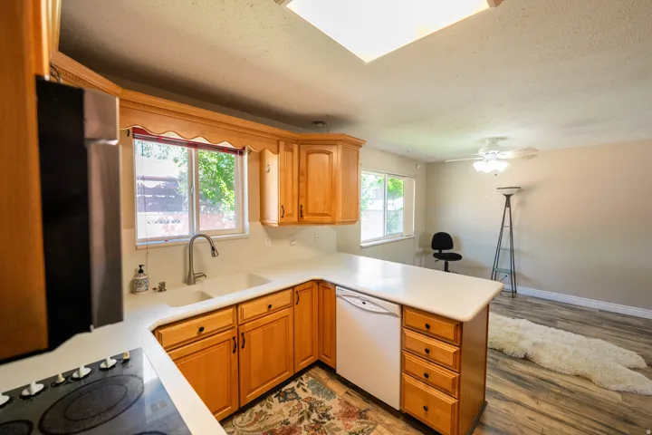 Kitchen with wood-finish cabinetry, white countertops, and a stainless steel sink with a gooseneck faucet