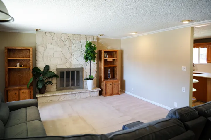 Stone-clad fireplace with hearth, recessed lighting, crown molding, and built-in wood cabinetry