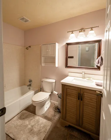 Bathroom featuring a built-in vanity with louvered doors, white countertop, and an integrated sink