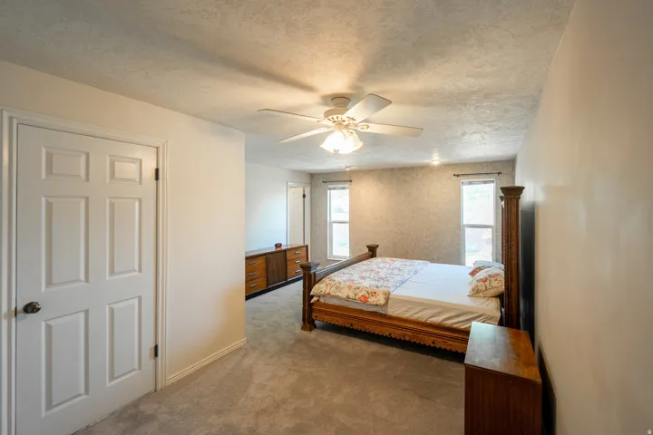 Carpeted room featuring a ceiling fan with integrated lighting, recessed lighting, and two windows