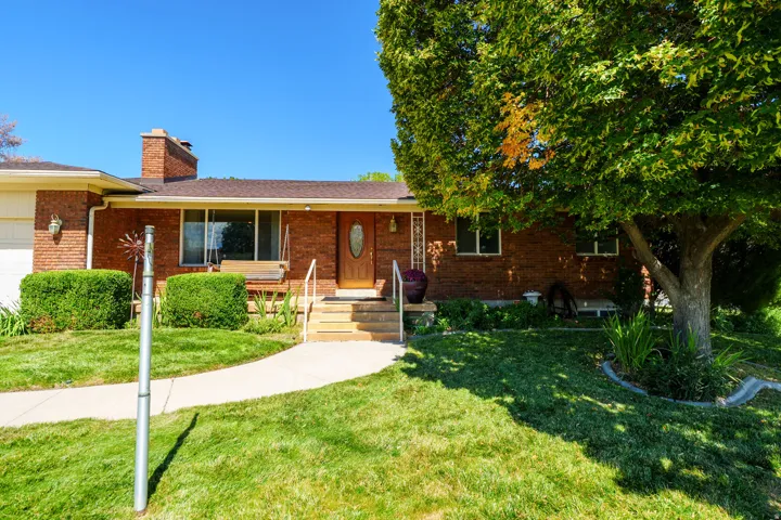 Brick exterior with an attached garage and a concrete pathway leading to the front entry