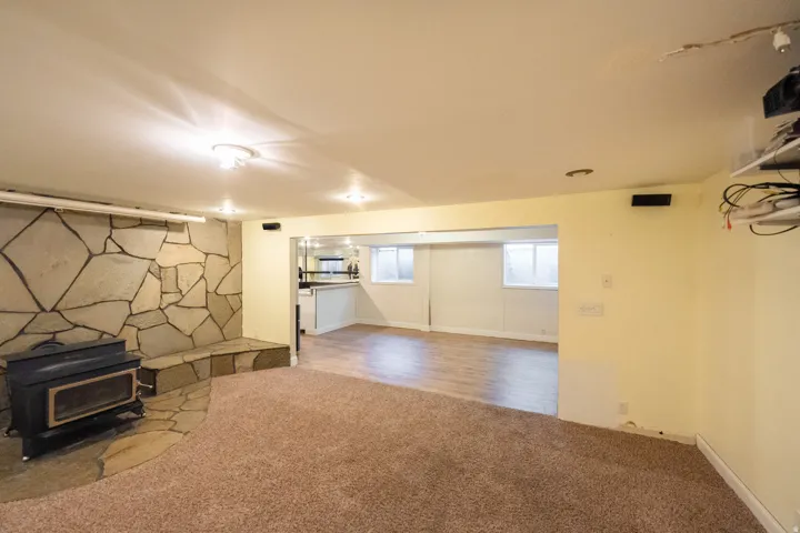 Stone accent wall with a wood-burning stove and hearth, recessed lighting, and carpeted flooring
