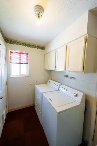 Laundry area featuring white cabinetry, a window with blinds, and a paneled door