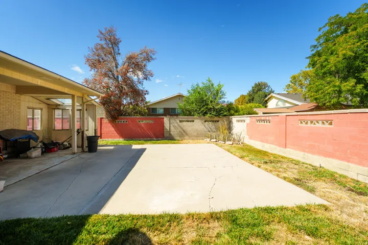 Expansive concrete patio area with a covered extension, enclosed by a perimeter wall featuring decorative block accents