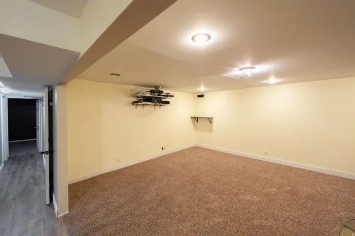 Carpeted room with recessed lighting and a wall-mounted shelf