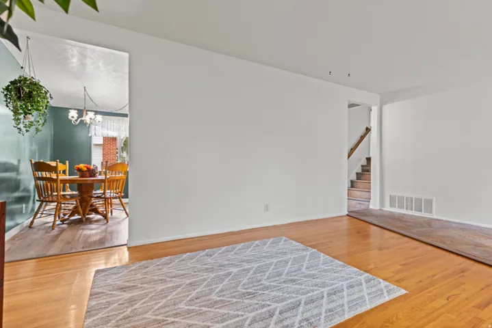 Hardwood flooring throughout the room, large picture window, white painted walls, and wood railing