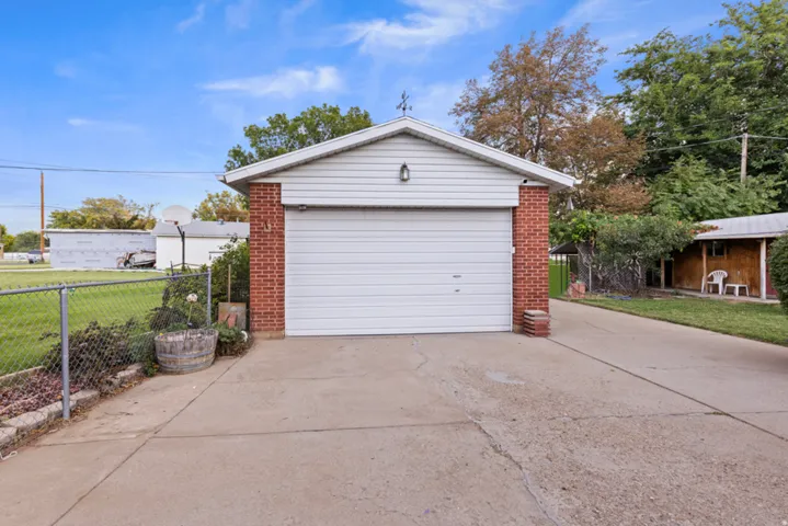 Attached garage with a white overhead door, brick accents, and a concrete driveway
