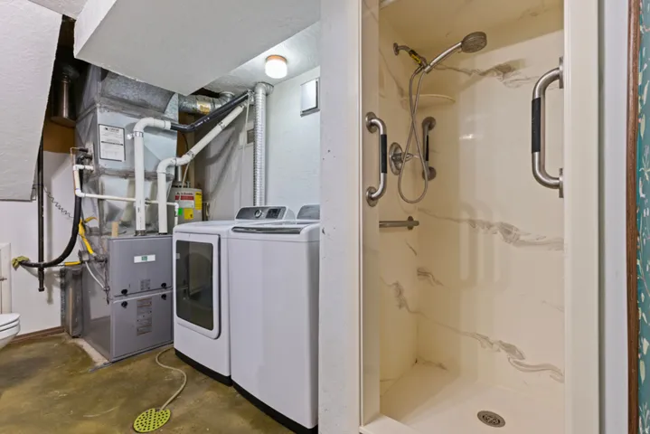 Walk-in shower with integrated grab bars, mounted showerhead, and a durable composite finish
