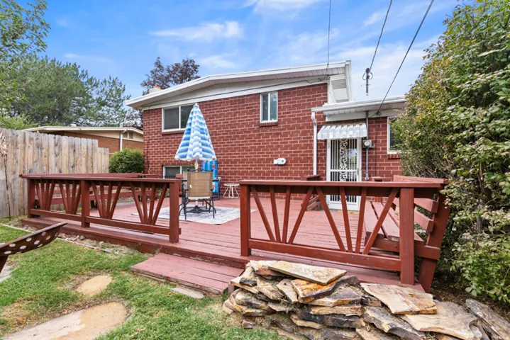 Expansive wood deck with a red finish, brick exterior, and white window awnings