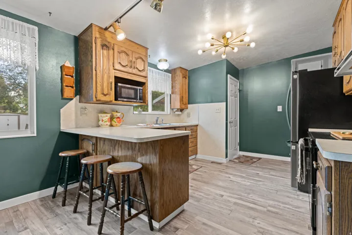 Wood-finish flooring with oak cabinetry, a built-in microwave, and a breakfast bar with seating