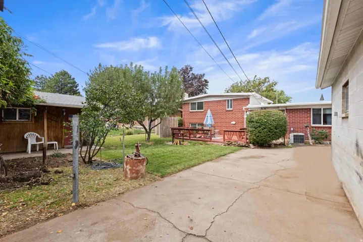 Expansive concrete driveway, mature trees, manicured lawn, and brick exterior