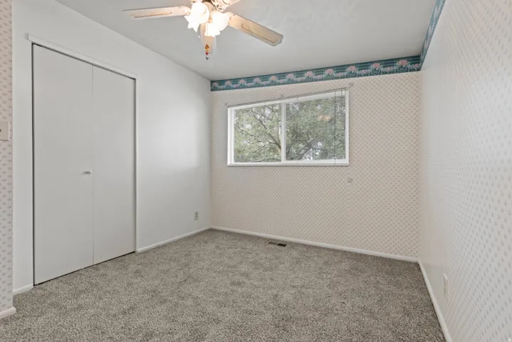 Wall-to-wall carpeting, dual-pane window, and a ceiling fan with integrated lighting