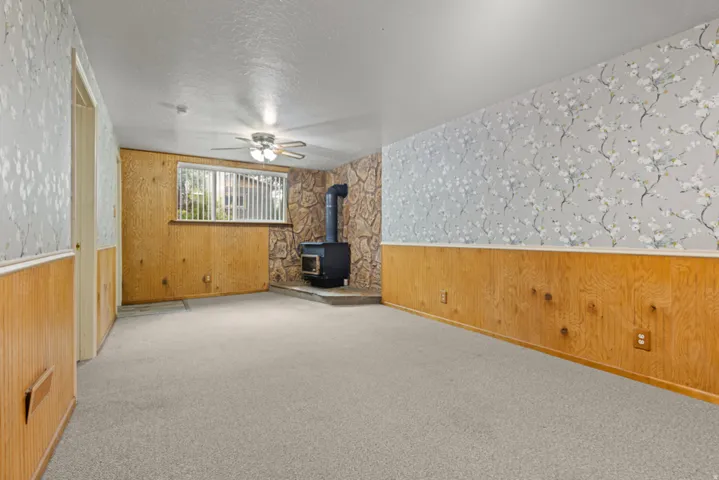 Wood-paneled walls and a stone accent wall frame a black wood-burning stove