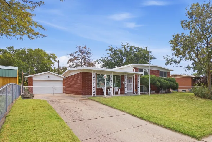 Red brick home with a covered front porch entry, a garage, and an extended driveway