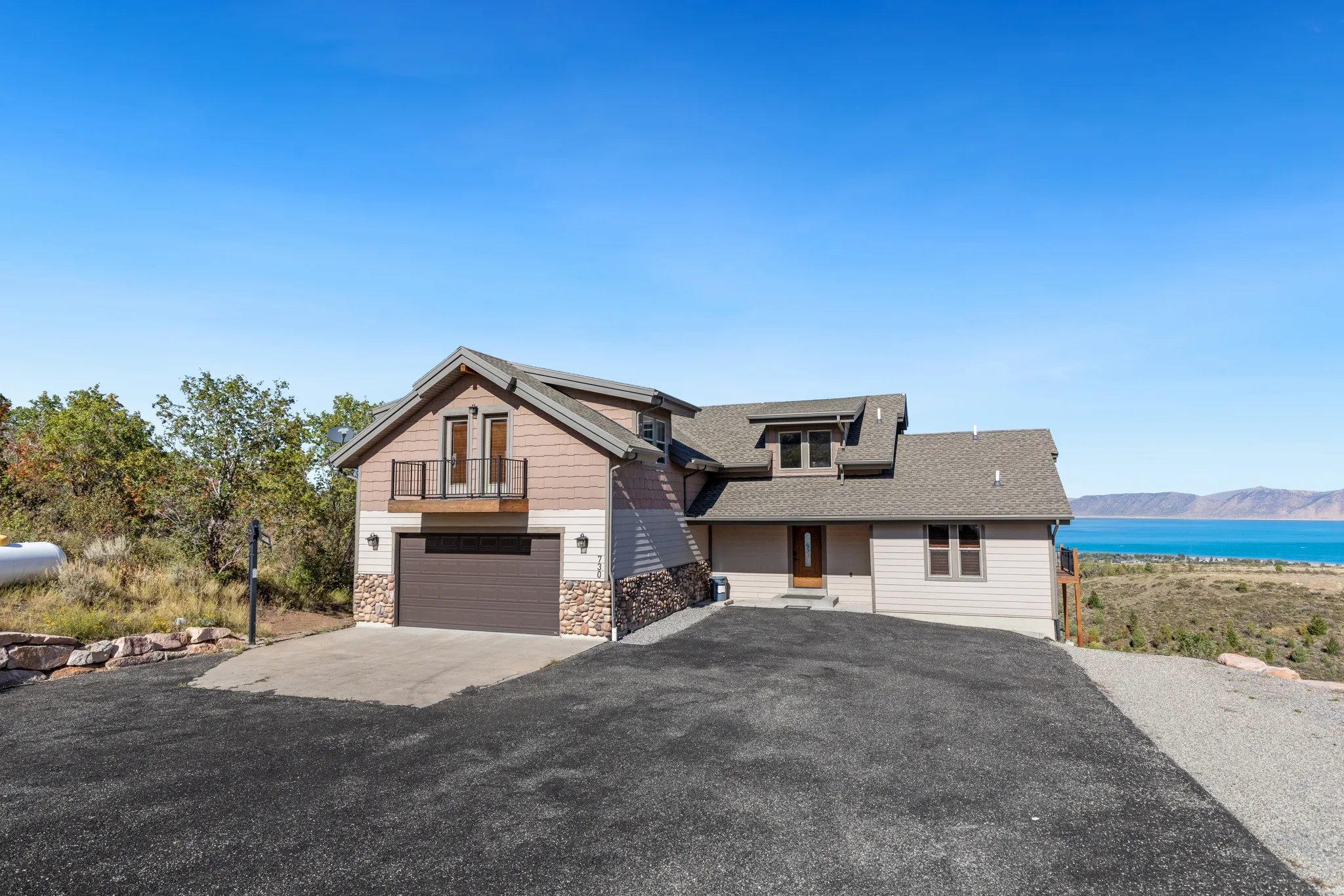 Multi-level home with stone veneer accents, an attached garage, and a second-story balcony