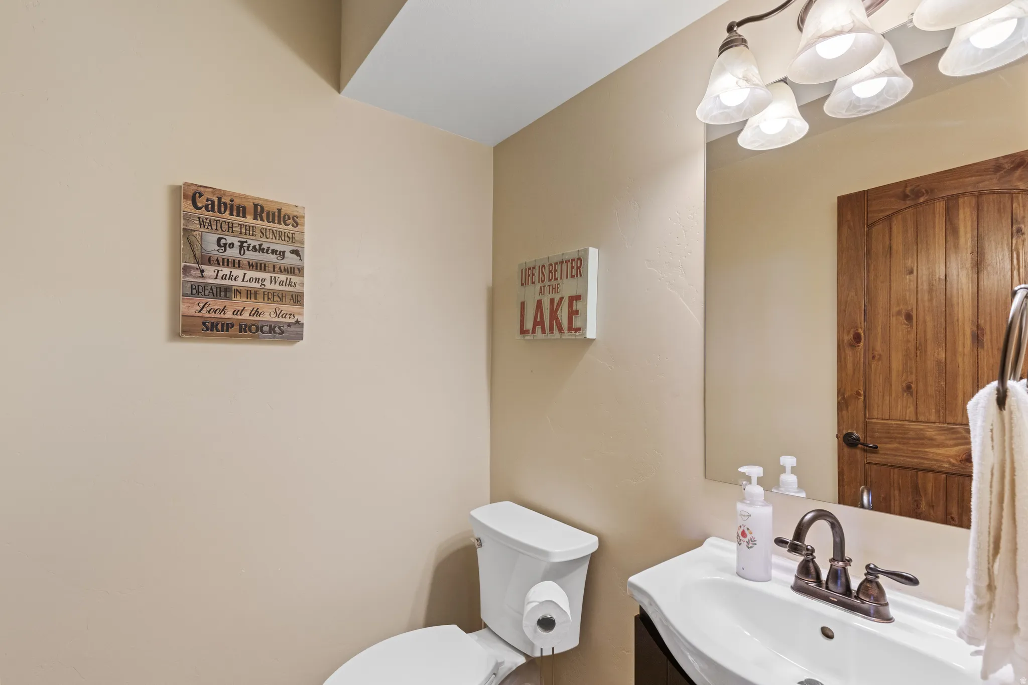 Pedestal vanity with an integrated basin, bronze-finish faucet, and a wall-mounted mirror