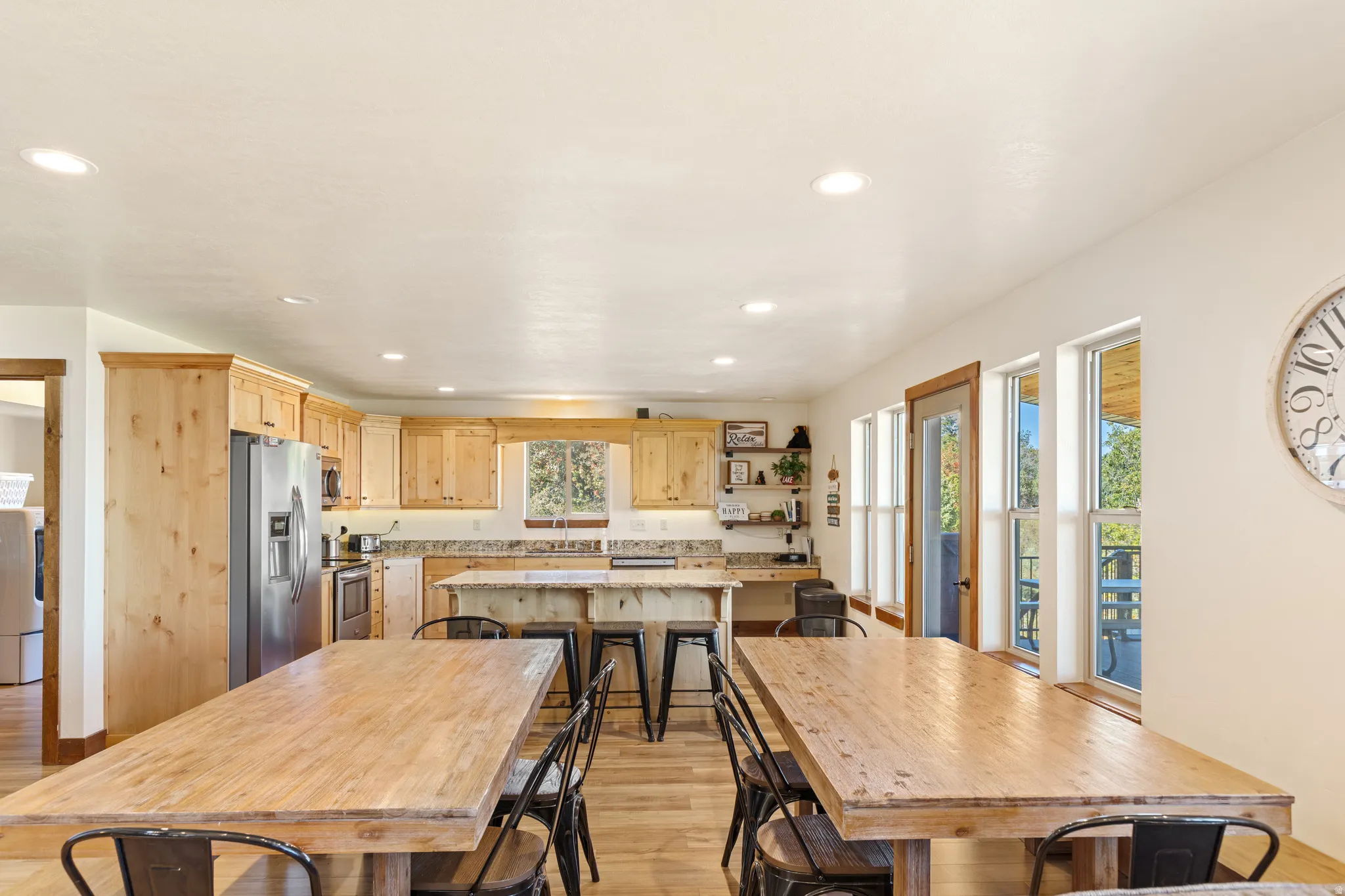 Kitchen with wood cabinetry, stainless steel appliances, a central island with bar seating, and wood-finish flooring