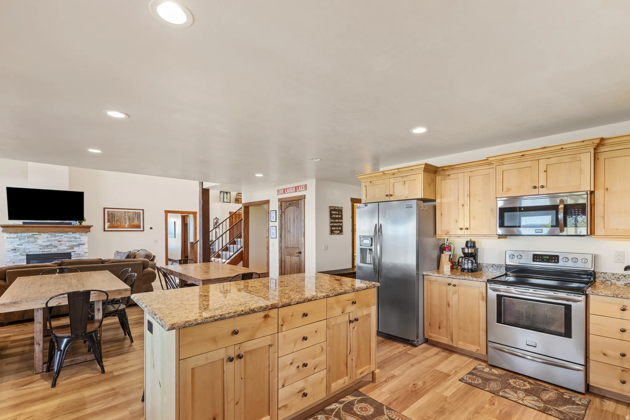 Kitchen featuring stainless steel appliances, light wood cabinetry, and a center island with a stone countertop