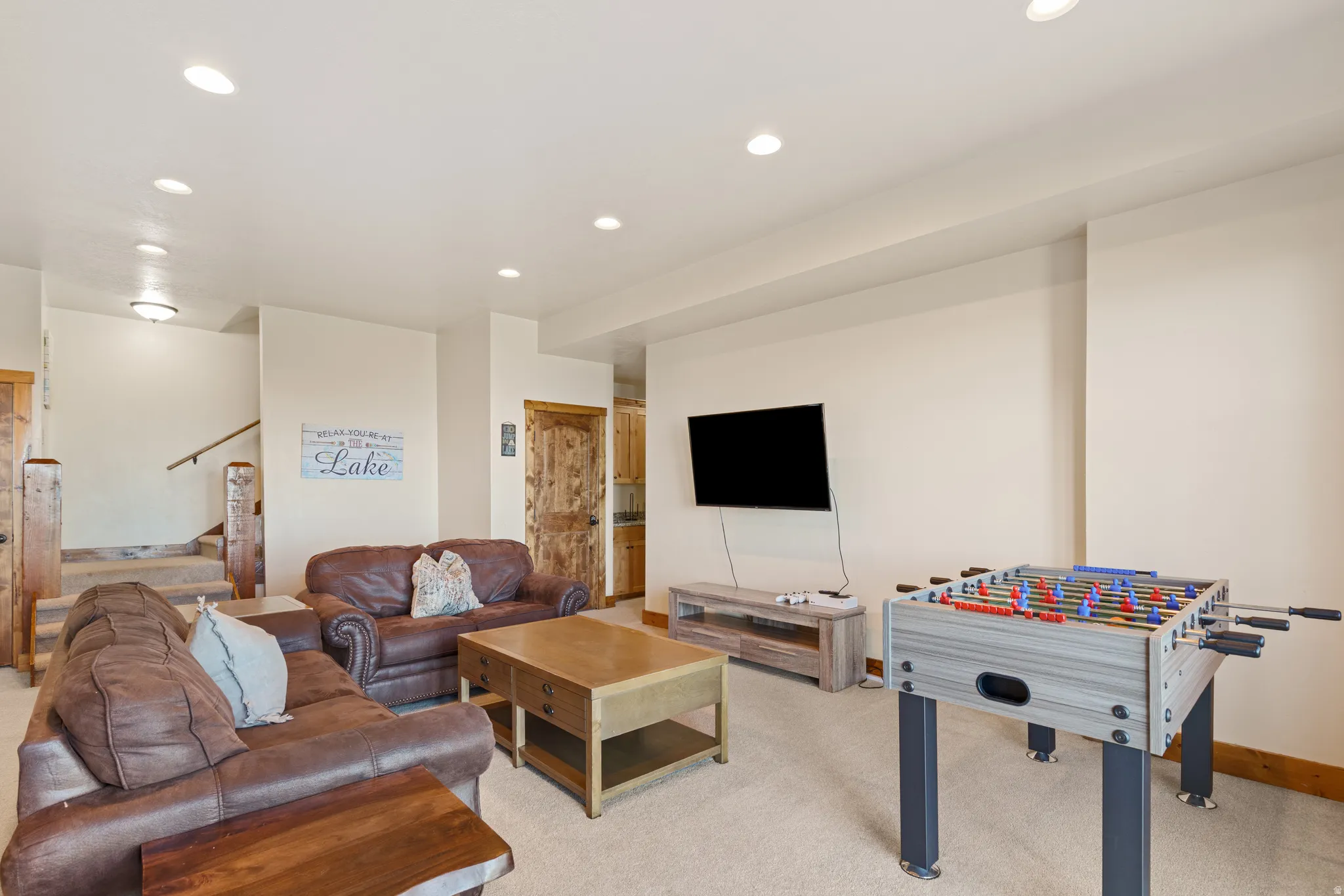 Recessed lighting illuminates a spacious room featuring a built-in entertainment center and a carpeted floor