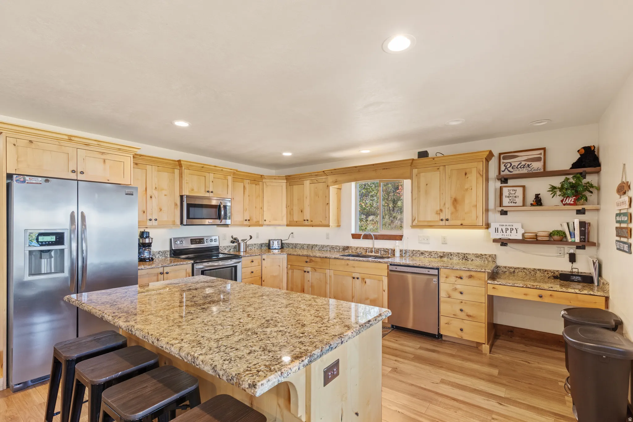 Kitchen featuring extensive wood cabinetry, granite countertops, stainless steel appliances, a center island, and wood-finish flooring