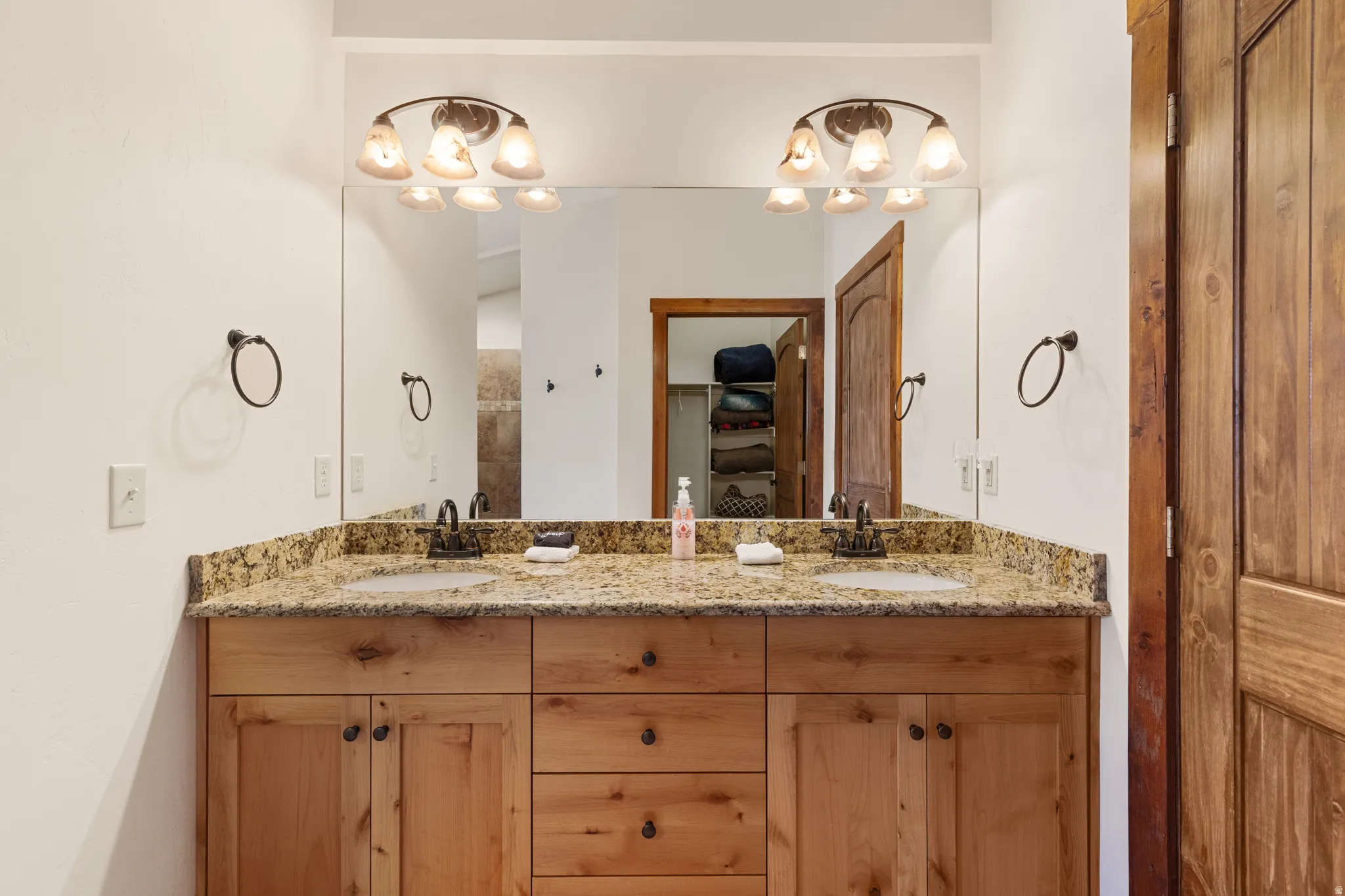 Dual vanity with stone countertop, two undermount sinks, and wood-finish cabinetry