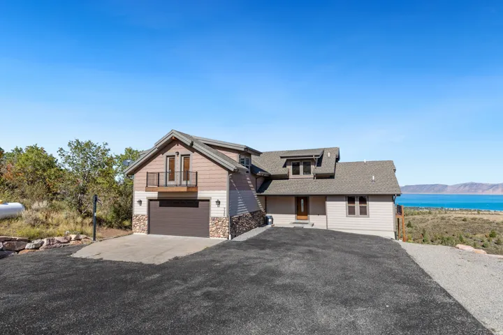 Multi-level home with stone veneer accents, an attached garage, and a second-story balcony