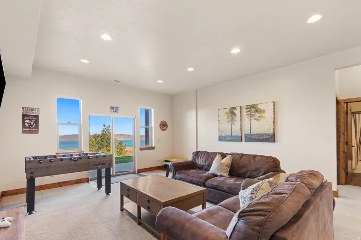 Recessed ceiling lighting, large windows with water scenery, sliding glass door, carpeted flooring, and wood-trim door frame
