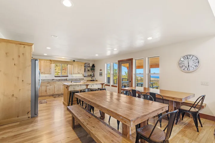 Spacious kitchen and dining area featuring light wood cabinetry, wood-finish flooring, recessed lighting, and large windows