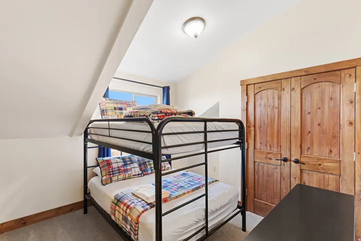 Room featuring wood-finish double doors with arched panels, sloped ceiling, recessed window, and carpeted flooring