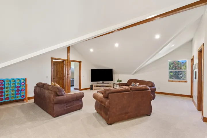 Spacious room featuring vaulted ceilings, recessed lighting, wood-finish trim, and neutral carpeting