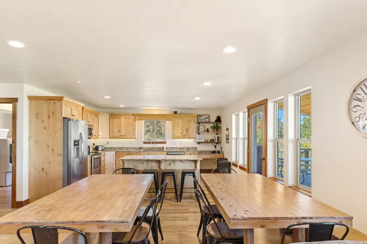 Kitchen with wood cabinetry, stainless steel appliances, a central island with bar seating, and wood-finish flooring