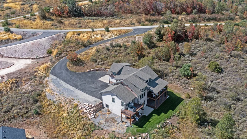 Multi-level residence featuring a gray shingle roof, light-colored exterior siding, multiple covered decks, and a manicured lawn