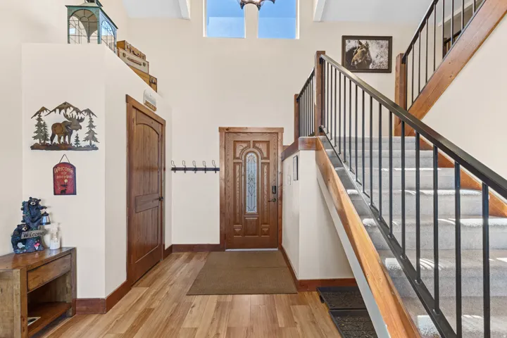 Two-story entryway featuring wood-finish flooring, a wood-paneled door with decorative glass, and a staircase with wood newel posts and metal balusters