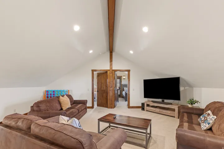 Vaulted ceiling with exposed wood beam, recessed lighting, and wood-finish doors