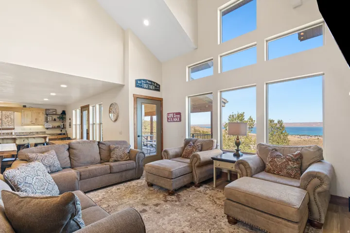 Vaulted ceiling with recessed lighting, large windows, wood-finish flooring, built-in cabinetry, and a glass-paneled door