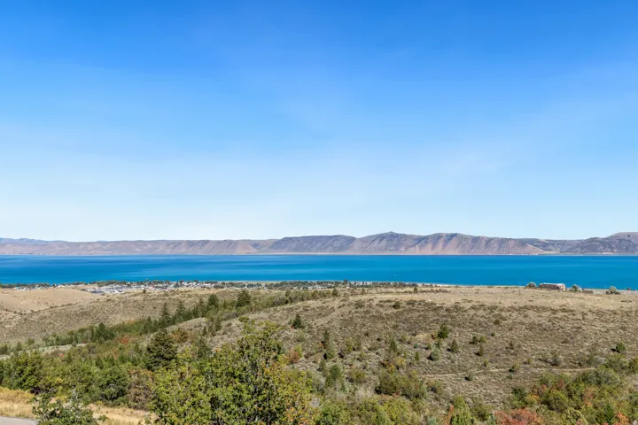 Expansive water body, mountainous terrain, and distant developed land under a clear sky