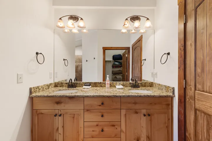Dual vanity with stone countertop, two undermount sinks, and wood-finish cabinetry