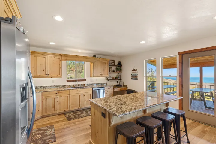 Kitchen featuring light wood cabinetry, granite countertops, stainless steel appliances, recessed lighting, and a kitchen island with seating
