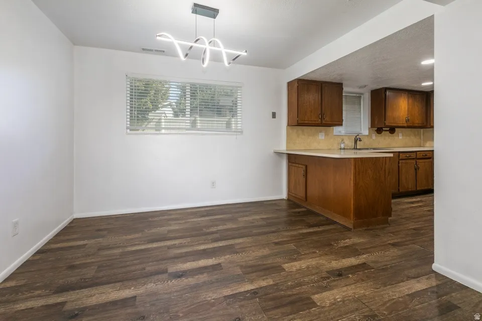 Wood-finish flooring, white walls, and a modern spiral pendant light fixture