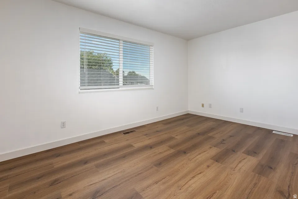 Wood-finish flooring, white walls, and horizontal window blinds