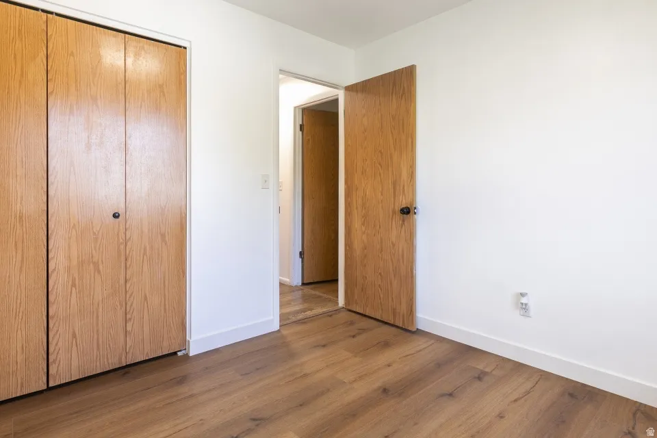 Wood-finish flooring, white walls, wood-paneled bifold closet doors, and wood-paneled interior doors